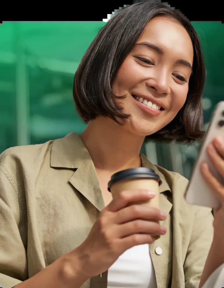 Mulher sorrindo, segurando o celular e um copo de café